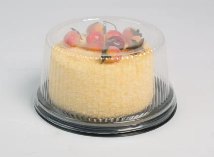 "Elegant JC Packaging clear cake dome encasing a yellow sponge cake topped with sugar-dusted strawberries and cherries, accentuating the dessert's allure."
