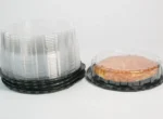 "Stack of JC Packaging's clear containers for cakes and tarts on black bases, featuring a delicious tart in a transparent package, ready for display."