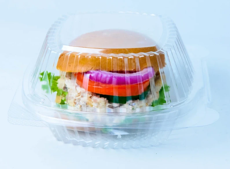 "A gourmet burger enclosed in a clear Burger Dome container from JC Packaging, highlighting the vibrant ingredients."