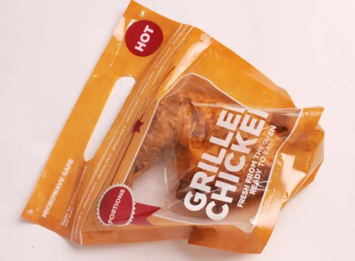 "Damaged grilled chicken packaging from www.jcpackaging.net featuring a microwave-safe label and HOT sticker, emphasizing quick meal prep."