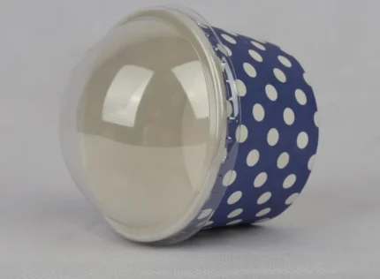 "A medium-sized ice cream cup adorned with white polka dots on a navy blue background, featuring a transparent dome lid, from www.jcpackaging.net."