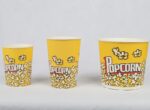 A lineup of three yellow popcorn buckets with the 'Popcorn' logo, from smallest to largest, from www.jcpackaging.net."