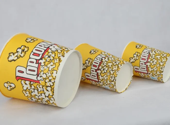 Assorted sizes of yellow popcorn buckets with a fun popcorn design, available at www.jcpackaging.net.