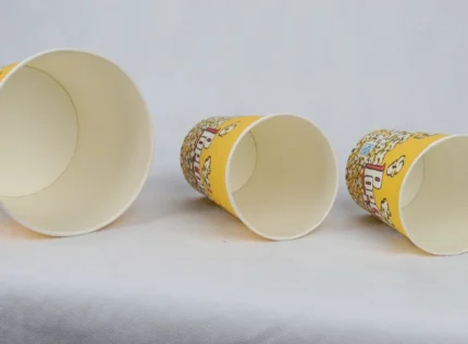 "Three varying sizes of yellow popcorn buckets with a classic cinema-style design from www.jcpackaging.net."