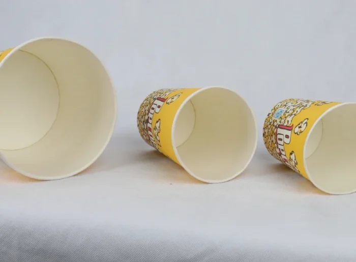 "Three varying sizes of yellow popcorn buckets with a classic cinema-style design from www.jcpackaging.net."