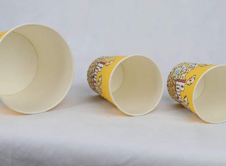 "Three varying sizes of yellow popcorn buckets with a classic cinema-style design from www.jcpackaging.net."
