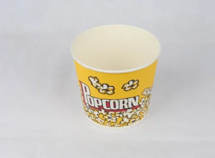 "A large 46oz yellow popcorn bucket with a playful design from www.jcpackaging.net stands ready for your next movie night."