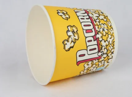 "A large 85oz yellow popcorn bucket full of character with popping kernel designs, available at www.jcpackaging.net."
