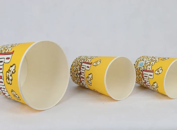 "Three yellow popcorn buckets tipped on their sides showcase the classic popcorn design from www.jcpackaging.net."