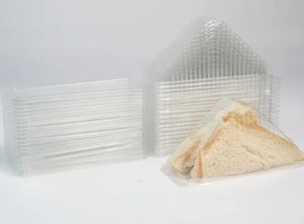 "A fresh sandwich triangle in a clear JC Packaging wedge container, showcasing quality and convenience - visit jcpackaging.net."