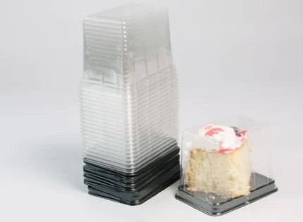 "Clear plastic cake slice packaging by JC Packaging showcasing a single slice of vanilla cake with whipped cream and a strawberry topping, demonstrating a secure and visually appealing presentation."
