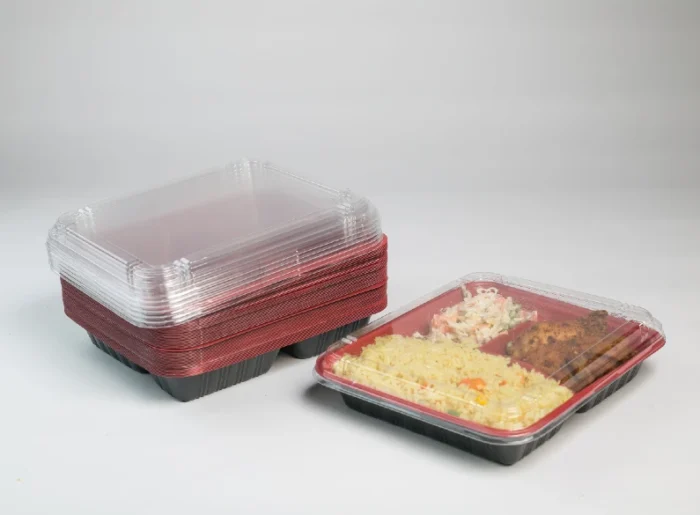 "Stack of red and clear clamshell meal trays with a filled tray in front, showcasing convenient meal portioning by JC Packaging."