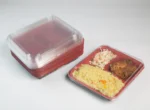 "JC Packaging's stack of clear-lid 3-division takeout containers next to a sample container filled with a delectable meal, showcasing efficiency and presentation."